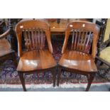 A pair of Edwardian mahogany chairs with curving back rails, vertical tie bars, solid seat on