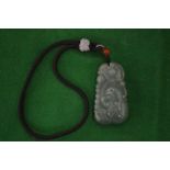 A Chinese carved jade pendant suspended from a cord.
