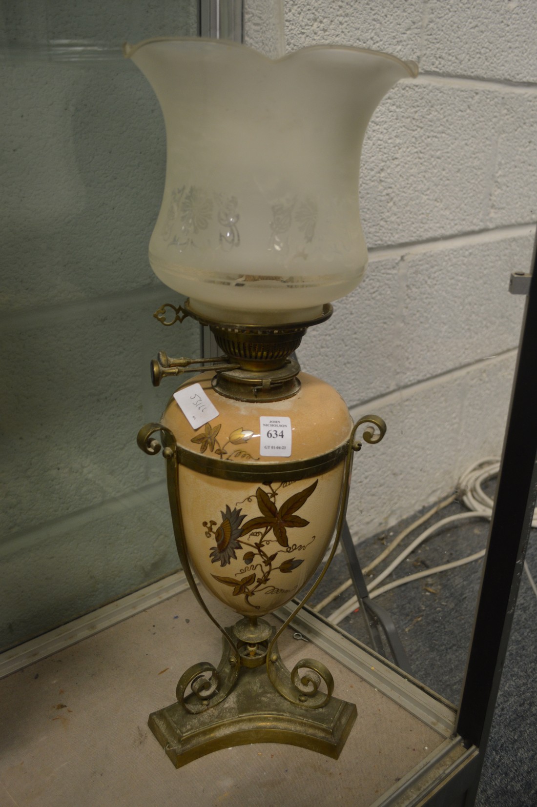 A brass and gilt decorated pottery oil lamp with decorative shade.