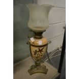 A brass and gilt decorated pottery oil lamp with decorative shade.