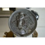 A circular cast lead plaque depicting an angel.