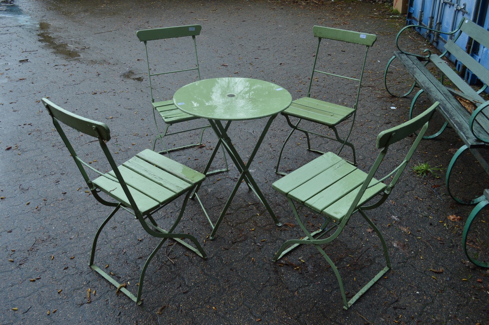 A metal circular folding patio table with four folding chairs.