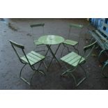 A metal circular folding patio table with four folding chairs.