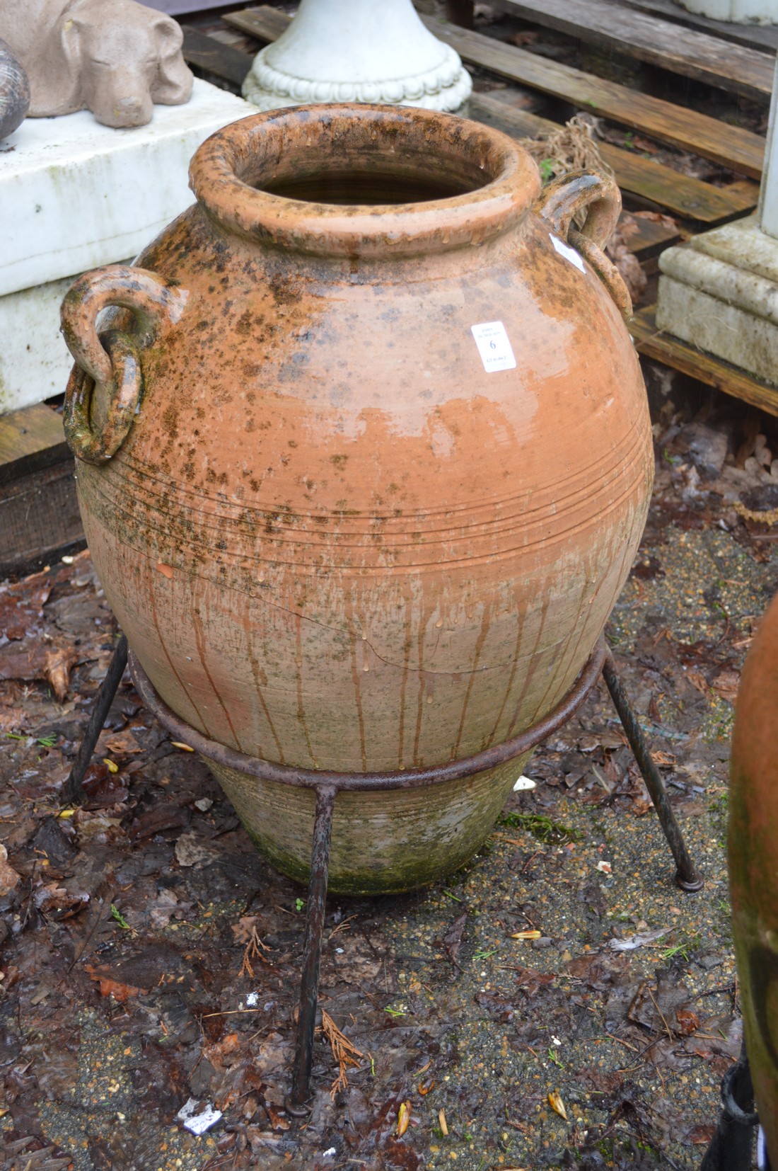 A terracotta urn on wrought iron stand.