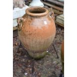 A terracotta urn on wrought iron stand.