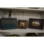 A miniature set of books, miniature portrait of a gentleman and a framed pot lid.