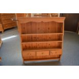 A pine shelving unit with three small drawers.