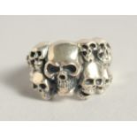 A SILVER RING WITH TEN SKULLS.