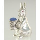 A SILVER PLATE PETER RABBIT PIN CUSHION, 5cm.