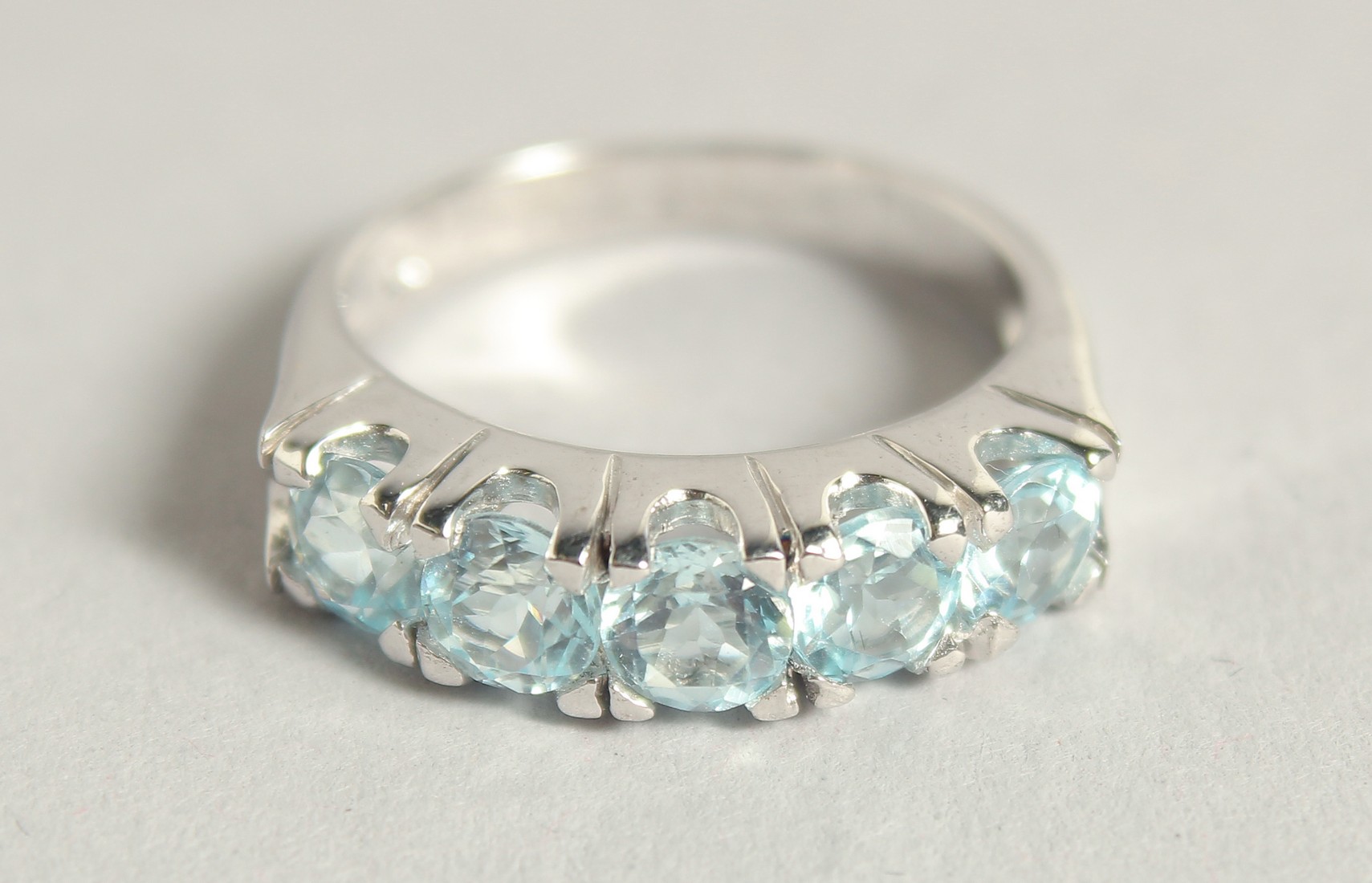 A SILVER BLUE TOPAZ HALF ETERNITY RING.