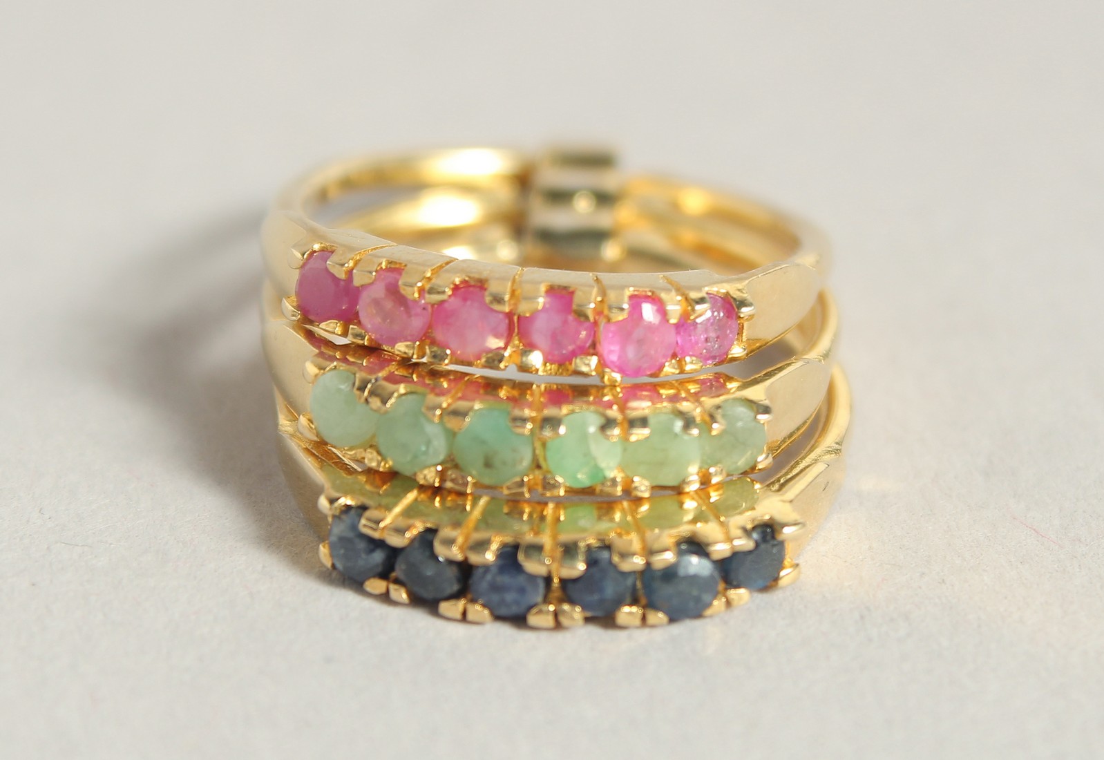 A SILVER AND 18 CT GOLD PLATED SAPPHIRE RUBY AND EMERALD STACK RING.