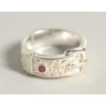 A SILVER OPAL AND RUBY BUCKLE RING.