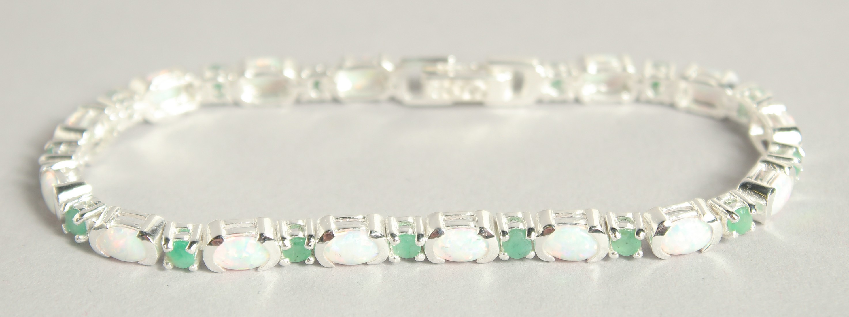 A SILVER OPAL AND EMERALD LINE BRACELET.