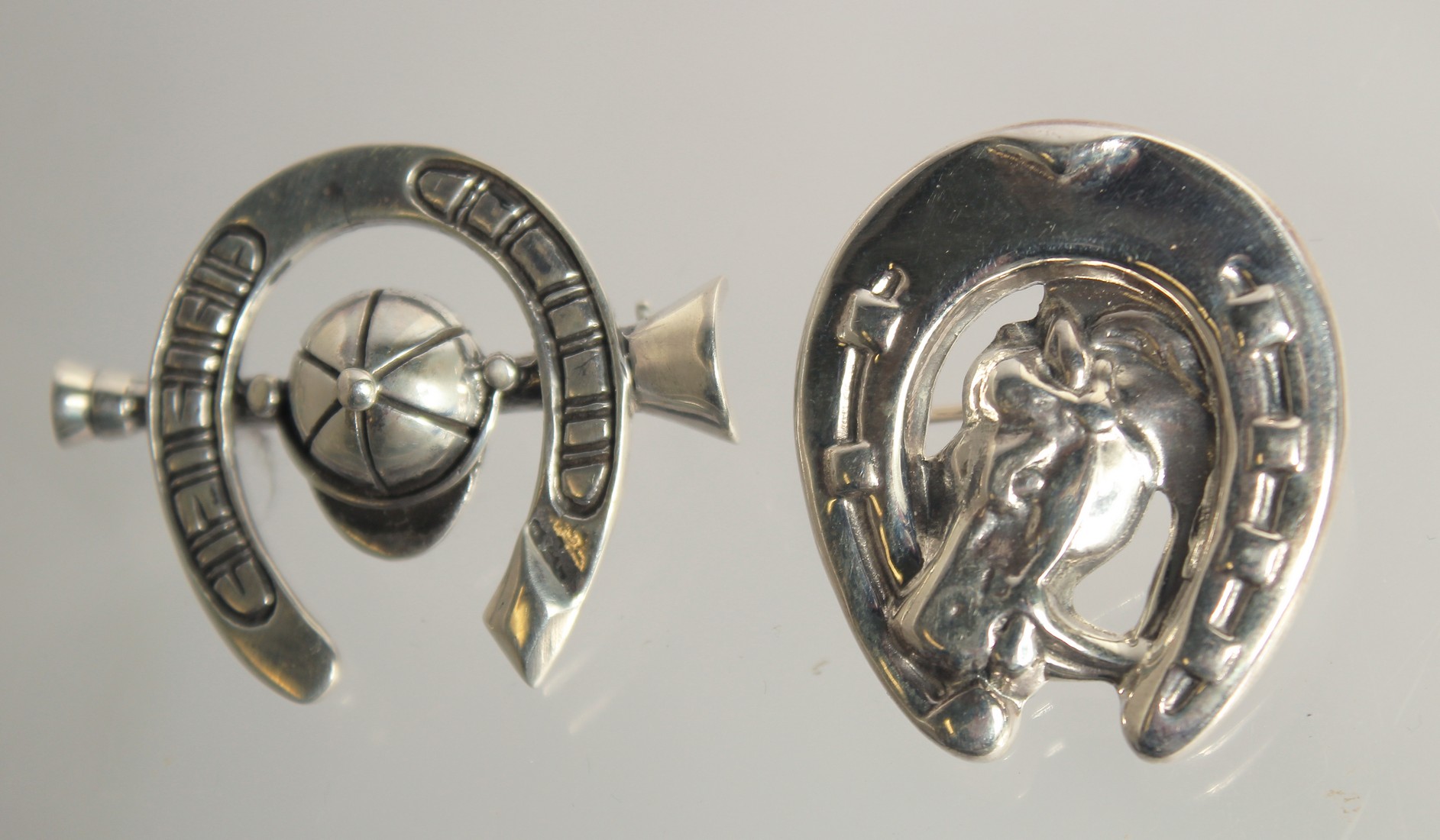 TWO SILVER HORSESHOE BROOCHES.