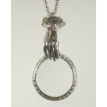 A SILVER HAND MAGNIFYING GLASS ON A CHAIN.