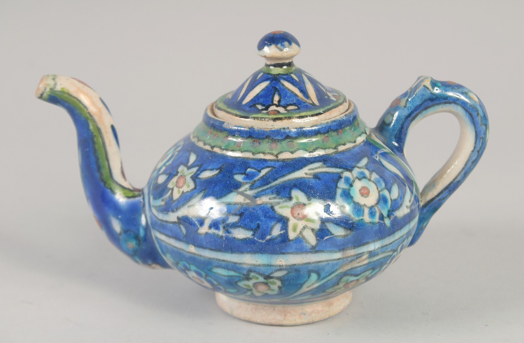 A PALISTINIAN GLAZED POTTERY TEAPOT, with foliate decoration, 19cm spout to handle.