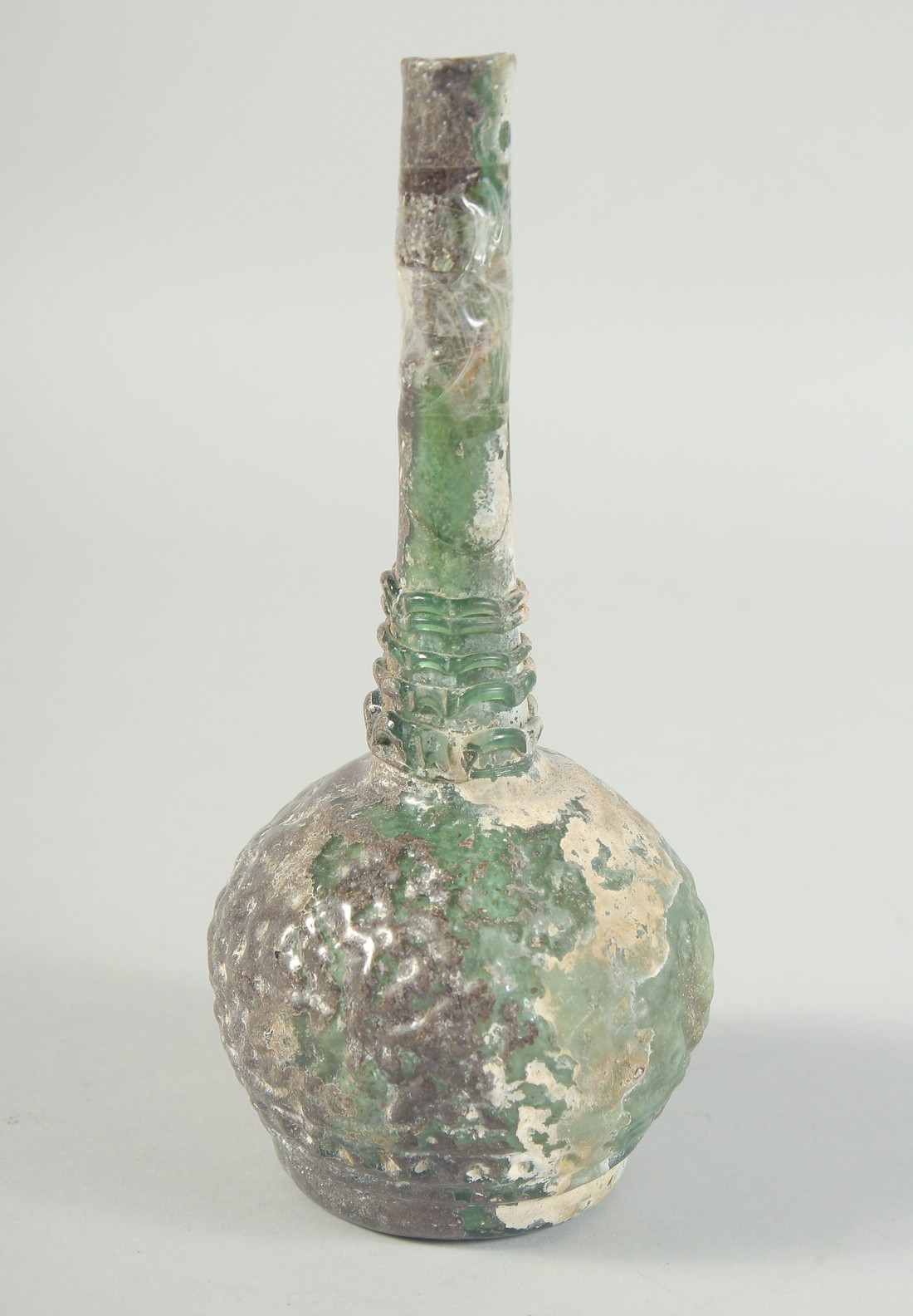 AN EARLY ISLAMIC GREEN GLASS BOTTLE, 20cm high.
