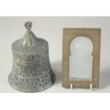 A SMALL EMBOSSED METAL MIRROR, together with another Islamic engraved metal item, (2)