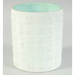 A CHINESE WHITE AND TURQUOISE GLAZE PORCELAIN BRUSH POT, with relief columns of characters, the base