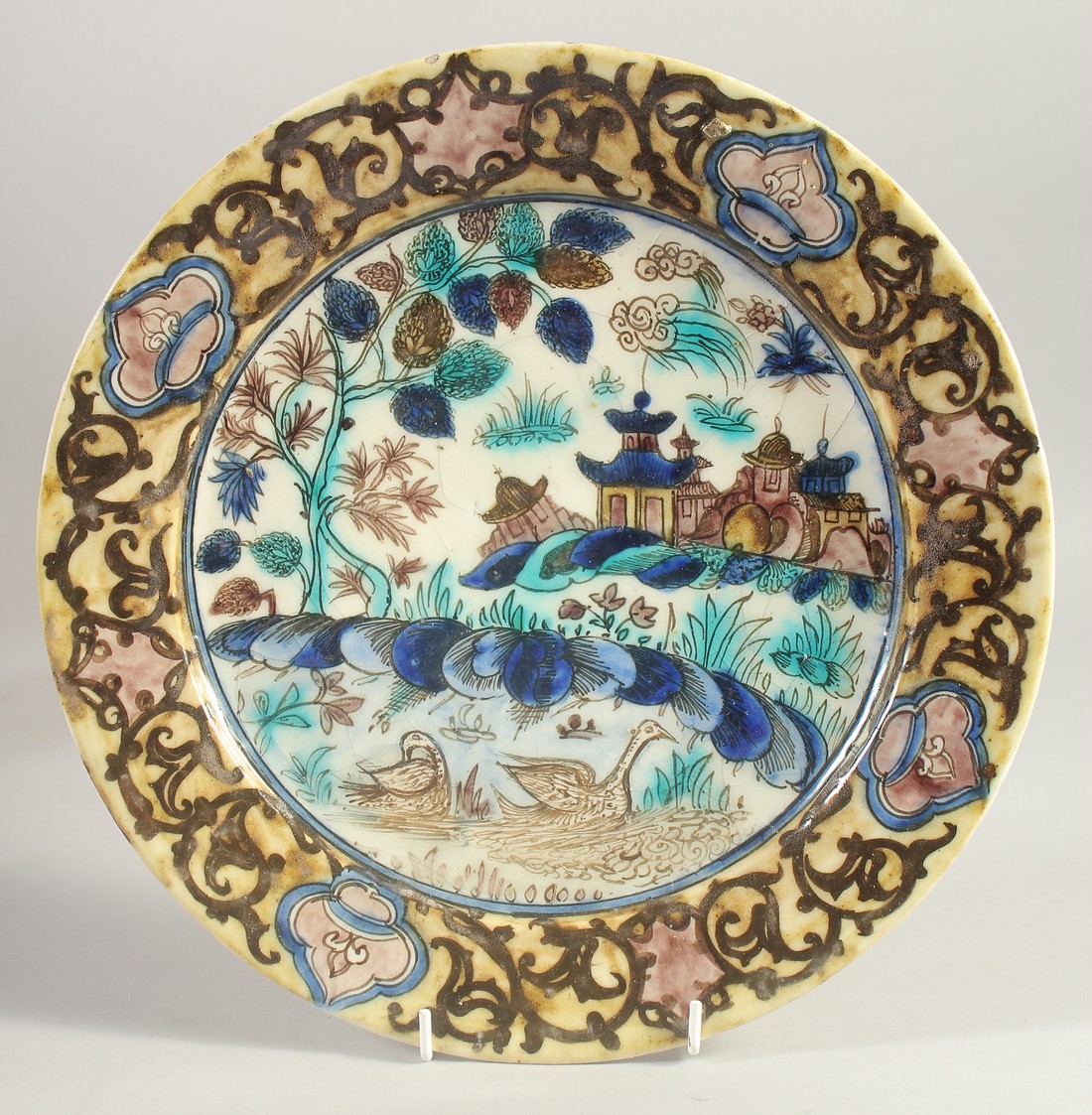 A RARE AND UNUSUAL PERSIAN - CHINESE MARKET GLAZED POTTERY DISH, 30cm diameter.