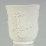 A CHINESE BLANC-DE-CHINE BEAKER, with relief floral decoration, 7.5cm high, 7.5cm diameter.