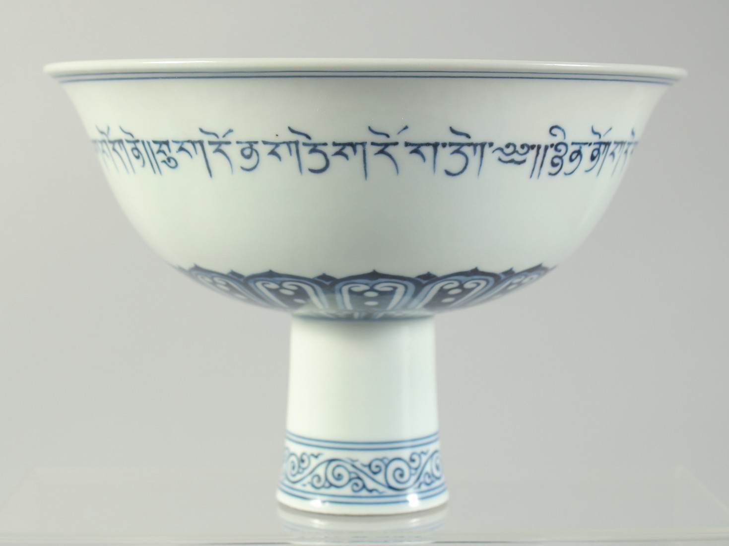 A BLUE AND WHITE PORCELAIN PEDESTAL BOWL, the exterior with a band of characters, interior centre