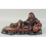 A CHINESE CARVED HARDWOOD FIGURE OF AN IMMORTAL, on a fitted hardwood stand, 40cm long overall.