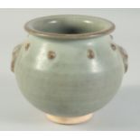 A CHINESE CELADON GLAZE POTTERY JAR, with molded lion mask handles and a band of raised bosses, 13.