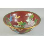 A LARGE CHINESE RED GROUND CLOISONNE BOWL, decorated with native flora, 25.5cm diameter.