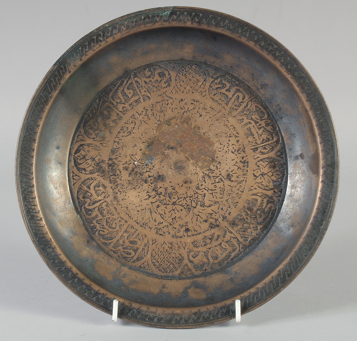 A 15TH CENTURY PERSIAN TIMURID ENGRAVED COPPER DISH, with panels of calligraphy, 23.5cm diameter.