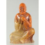 A CHINESE AMBER-COLOUR SOAPSTONE LUOHAN FIGURE, seal characters to base, 11.5cm high.
