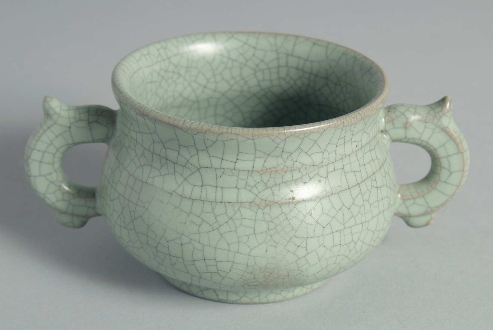 A CHINESE CELADON TWIN HANDLE CENSER, 15cm wide (handle to handle).