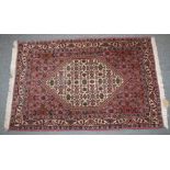 A SMALL PERSIAN RUG with stylised decoration on a rust ground. 106cm x 70cm.