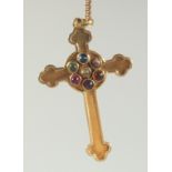 A 9CT GOLD CROSS on a chain, the cross inset with gemstones.