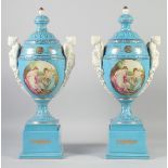 A LARGE PAIR OF CONTINENTAL LIGHT BLUE TWO HANDLED URNS AND COVERS with classical female heads, on