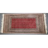 A PERSIAN RUG with stylised decoration on a red ground. 144cm x 66cm.