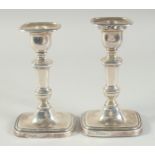 A PAIR OF SILVER CANDLESTICKS with rectangular loaded bases. 6.5ins high. Sheffield 1918. Maker: