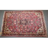 A PERSIAN RUG with floral design on a pink ground. 168cm x103cm.