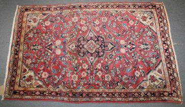A PERSIAN RUG with floral design on a pink ground. 168cm x103cm.