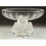 A LALIQUE CIRCULAR PEDESTAL BOWL, the base with four cherubs. and birds. Signed. 14ins diameter.