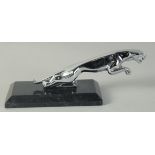 A JAGUAR CHROME MASCOT on a marble stand.