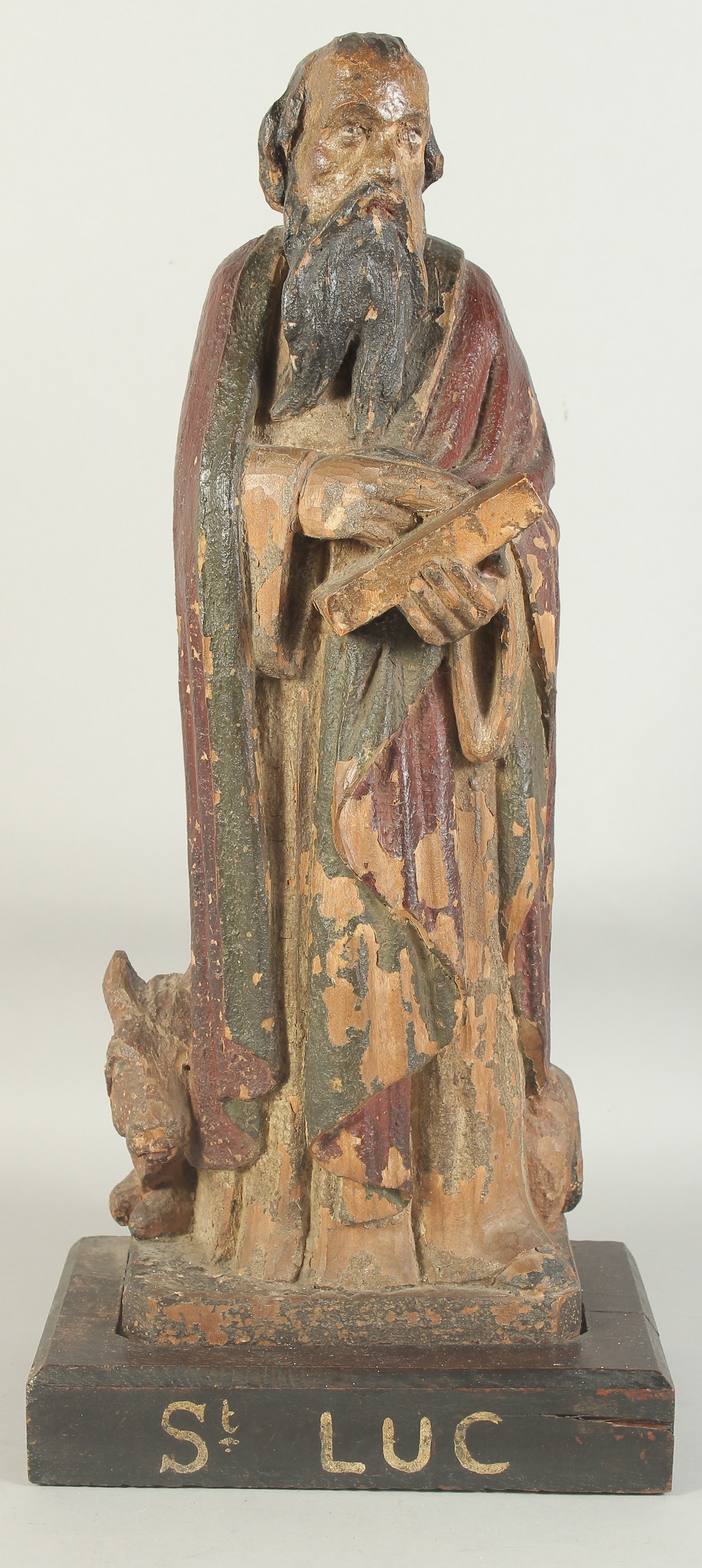 A GOOD 17TH CENTURY CARVED WOOD AND POLYCHROME FIGURE, ST. LUC, on a wooden base. 1ft 11ins high.