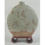 A CHINESE CELADON MOON FLASK on a wooden stand. 10ins high.