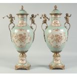 A PAIR OF PORCELAIN AND ORMOLU VASES AND COVERS painted with flowers with gilt cherub handles. 1ft