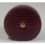 A BURGUNDY ROUND JEWELLERY BOX WITH VELVET INTERIOR AND GOLD INITIALS. 5ins diameter, 1.5ins deep.
