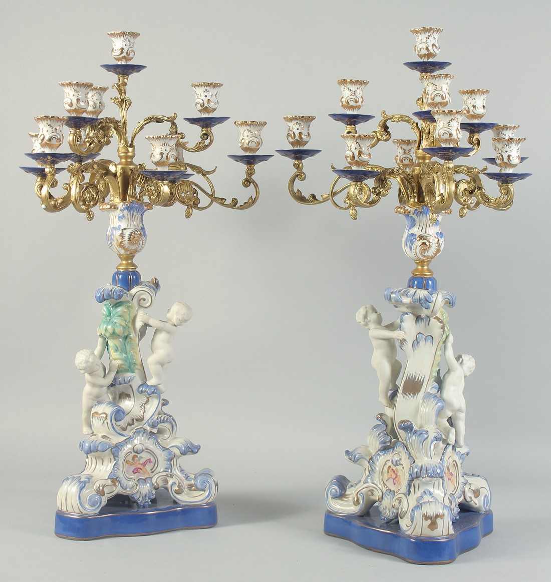 A GOOD PAIR OF SEVRES STYLE EIGHT BRANCH CANDELABRA with cupid support on blue bases. 1ft 11ins