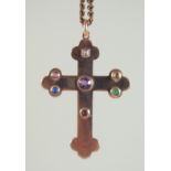 A 9CT GOLD CROSS on a chain, the cross inset with gemstones.
