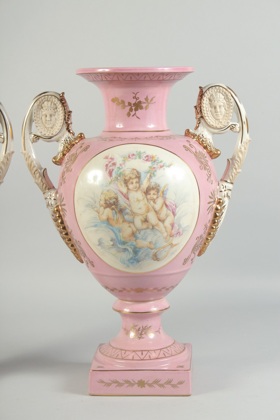 A PAIR OF SEVRES STYLE PINK TWO HANDLED VASES with oval panels of cupids. 1ft 4ins high. - Image 3 of 4