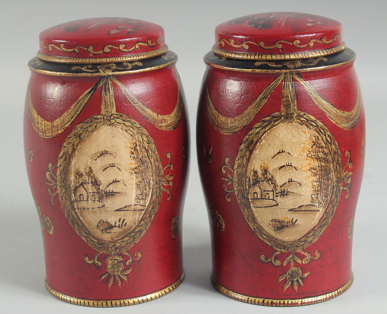 A SMALL PAIR OF RED TOLEWARE TINS AND COVERS. 7ins high.