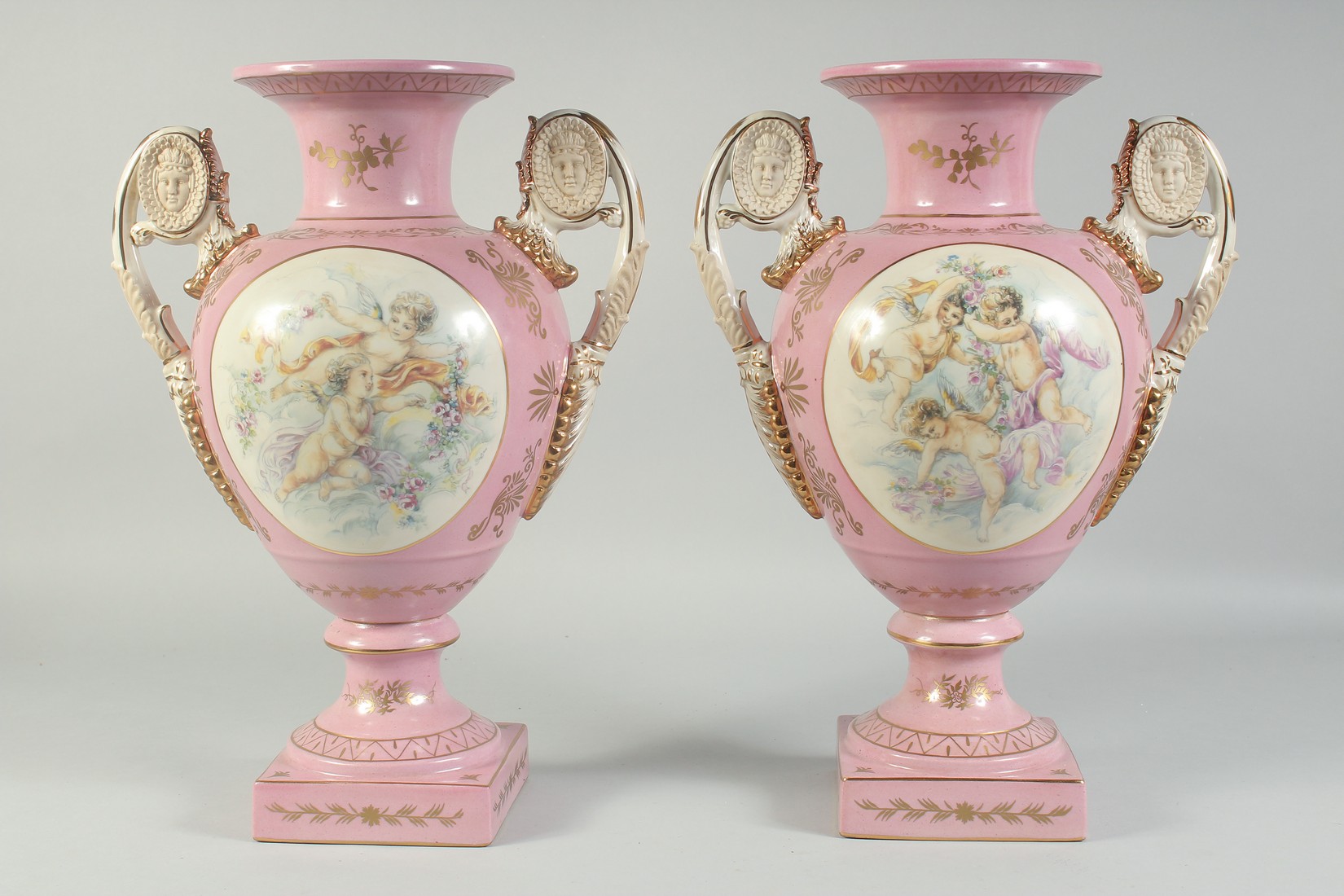 A PAIR OF SEVRES STYLE PINK TWO HANDLED VASES with oval panels of cupids. 1ft 4ins high. - Image 4 of 4